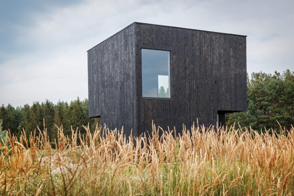 A shou sugi ban house surrounded by a field