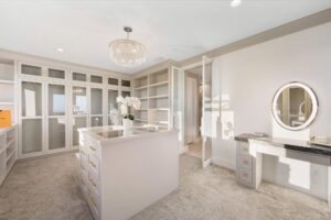 Luxurious walk-in closet with glass display cases, island, and vanity